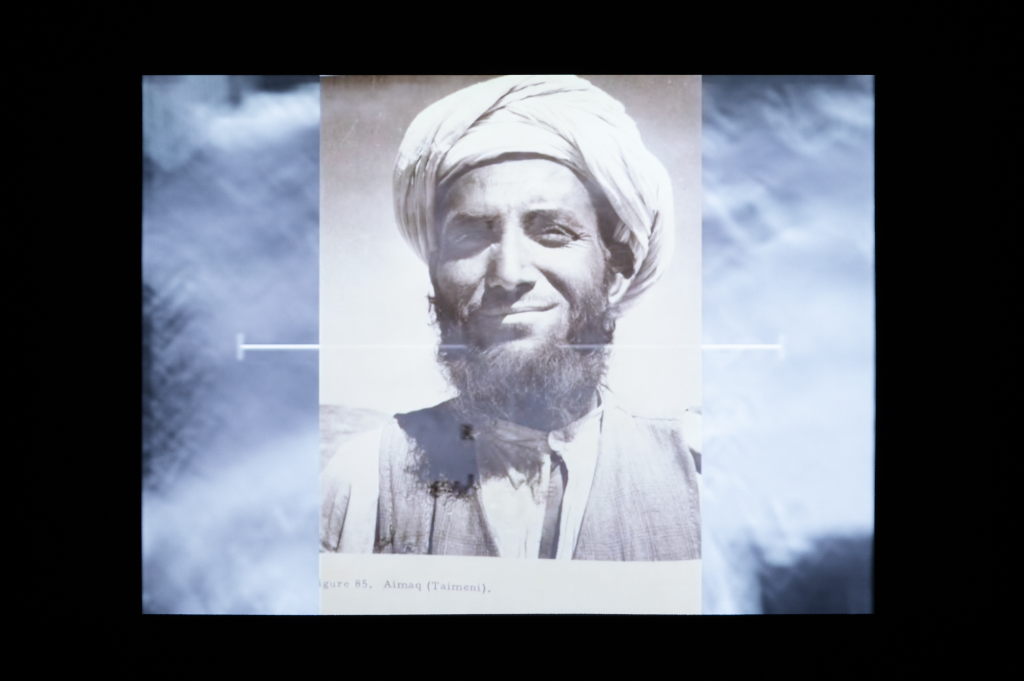 portrait of Afghani man overlaid on video of bombing in Afghanistan